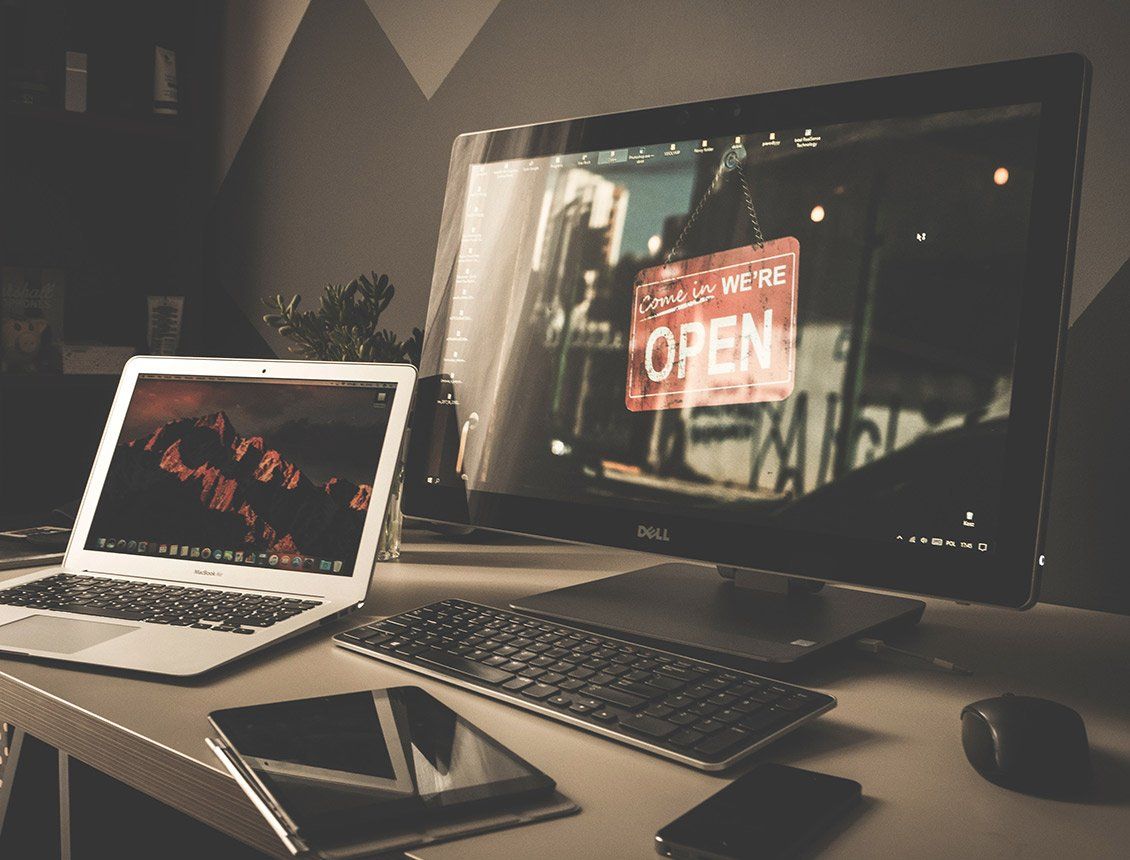 Laptop, monitor, keyboard, and tablet on a desk, a red 