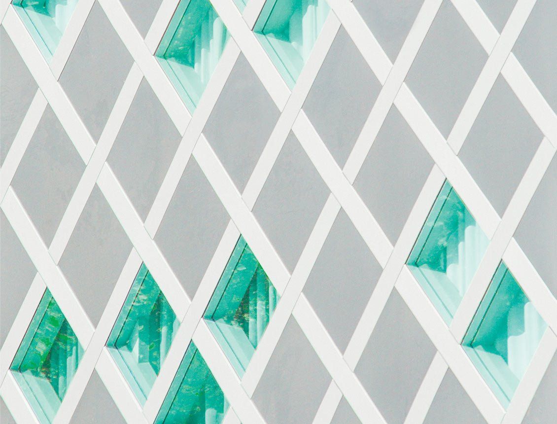 A close up of a white lattice with green triangles on a gray background.