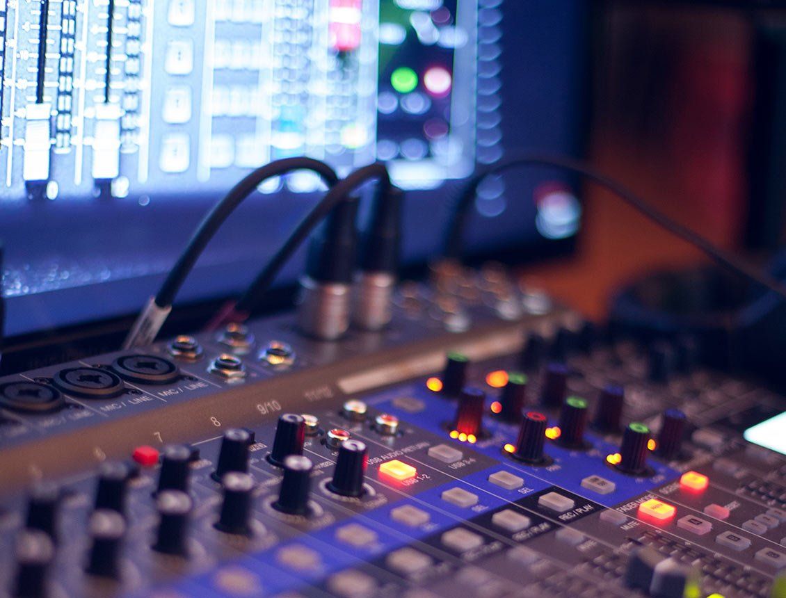 Audio mixing board with connected cables and a digital display showing audio levels.