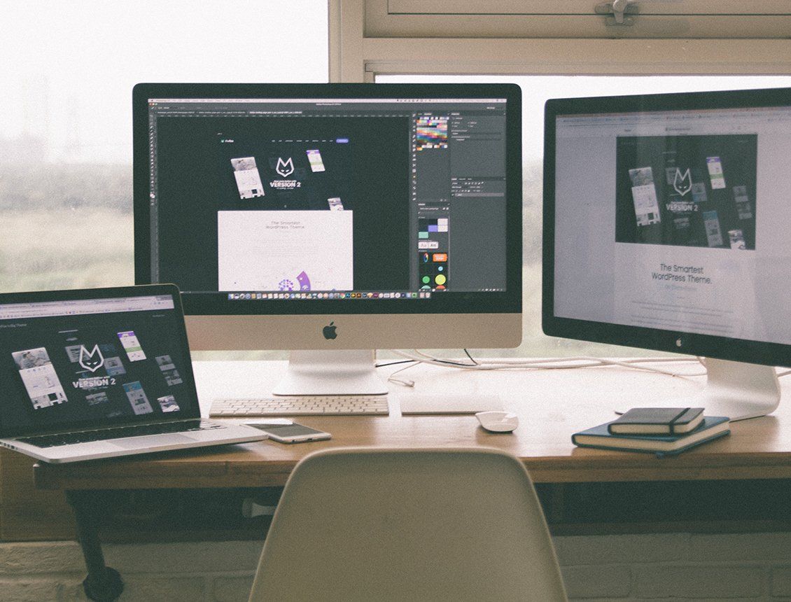 A desk with two computer monitors and a laptop
