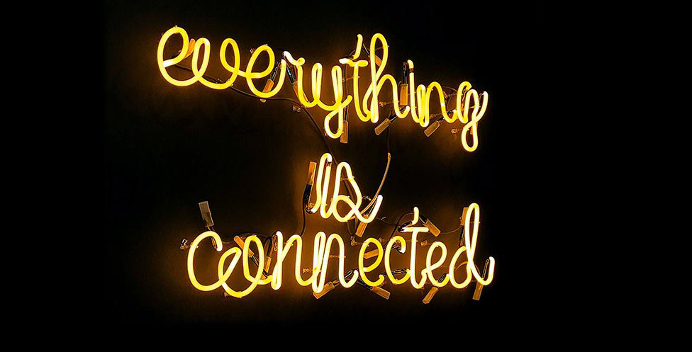 Image of neon sign over black that says A neon sign that says everything is connected