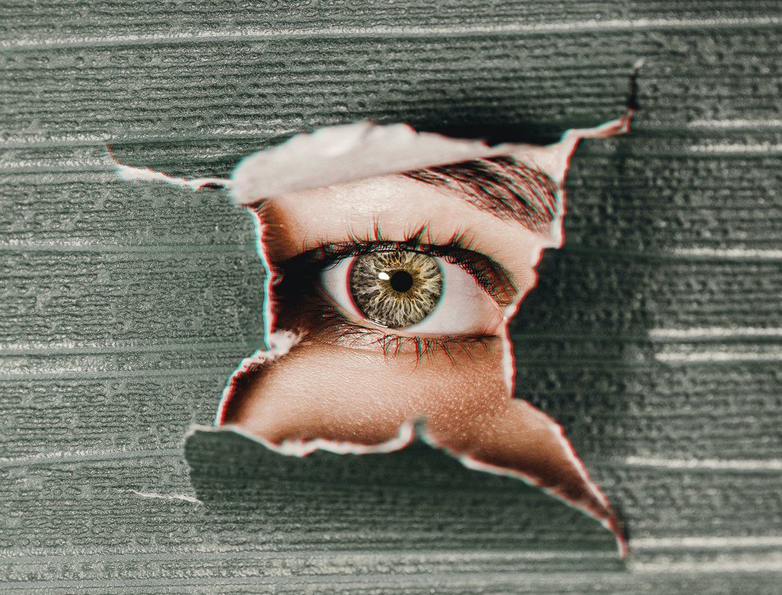 Image of a close up female eye looking through torn paper A woman 's eye is visible through a hole in a piece of paper.