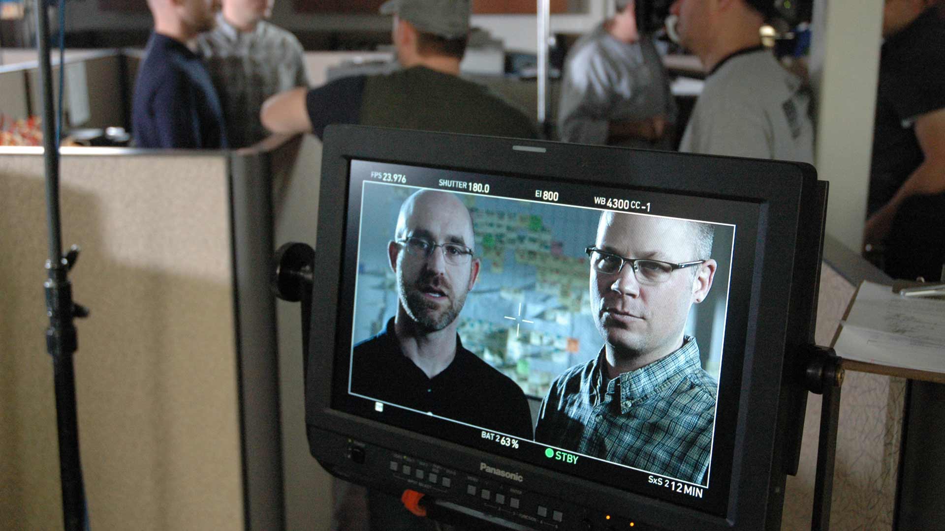 Genie Brand Film Behind the Scenes Monitor Engineers A group of men are watching a video on a monitor.