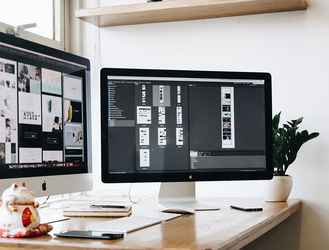 Two computer monitors are sitting on a wooden desk.