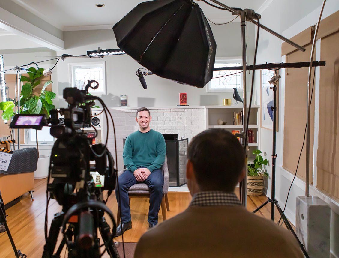 A man is sitting in front of a camera in a living room.