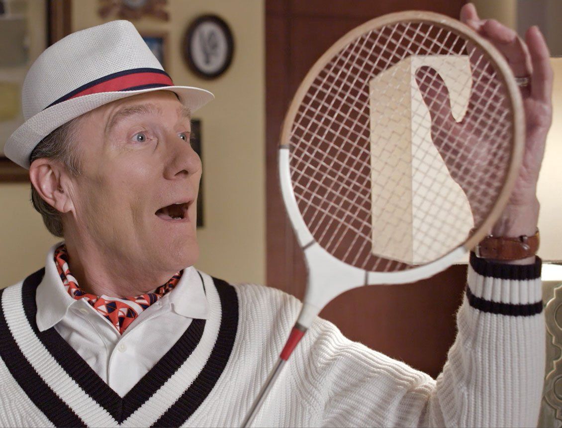 A man in a hat is holding a tennis racket with the letter r on it