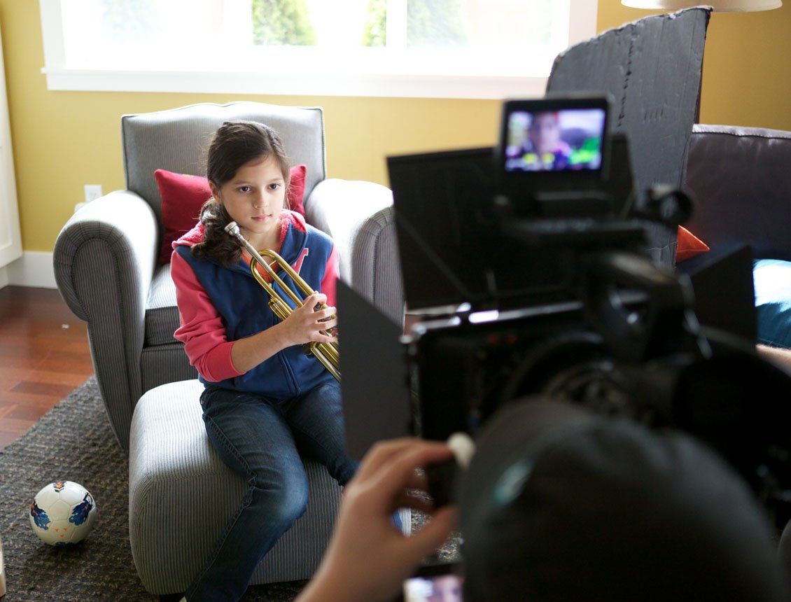 A young girl is sitting in a chair playing a trumpet