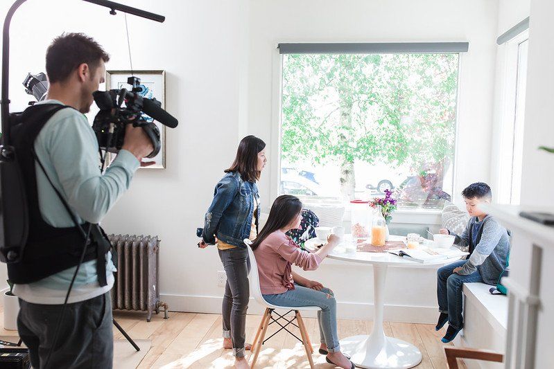 A man is taking a picture of a family in a living room.