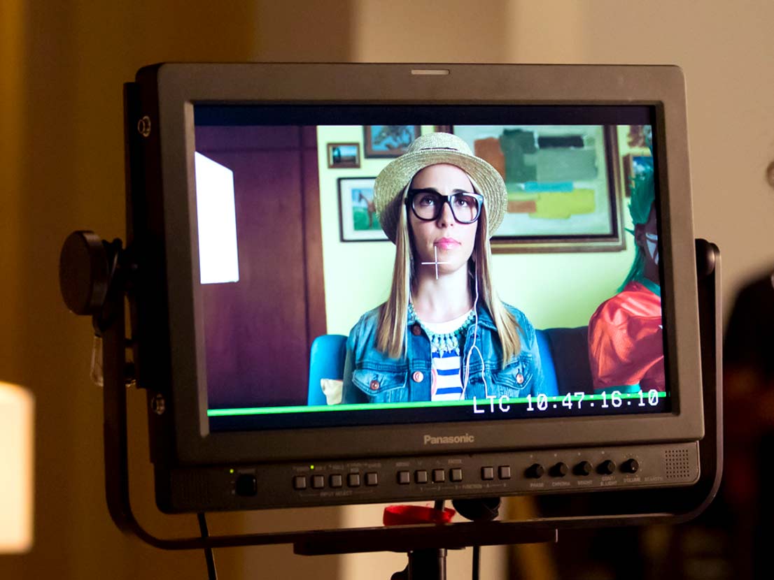 A panasonic monitor shows a woman wearing a hat and glasses