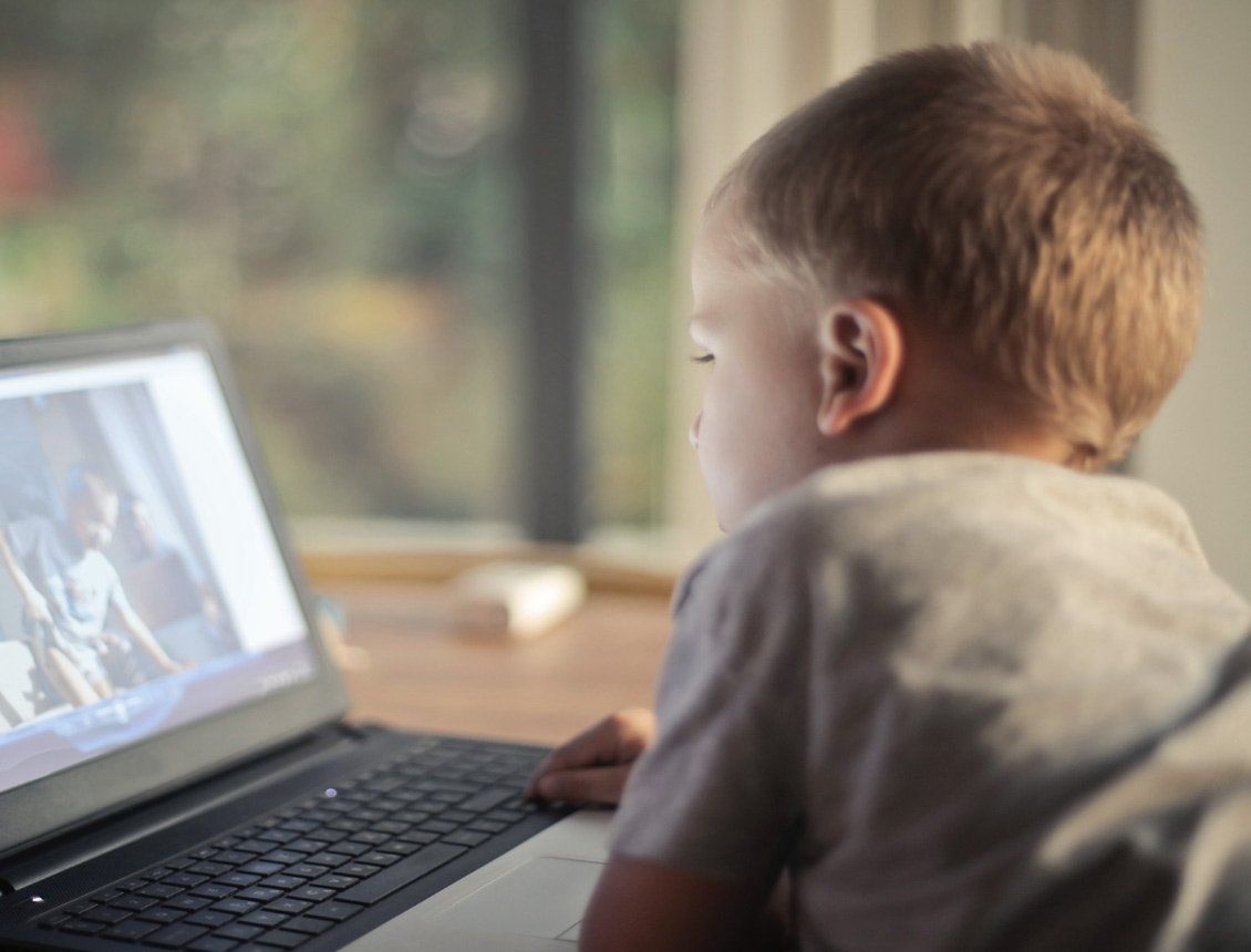A young boy is sitting in front of a laptop computer.