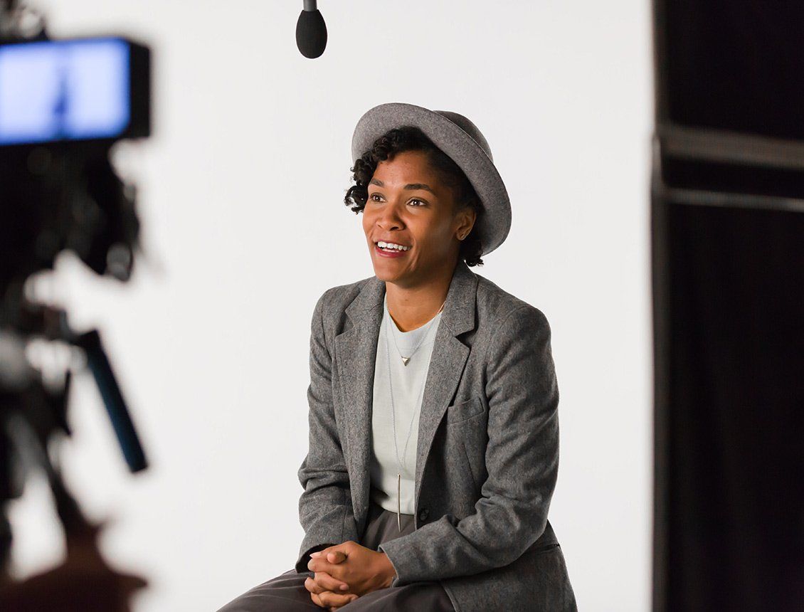 A woman in a hat is sitting in front of a camera.