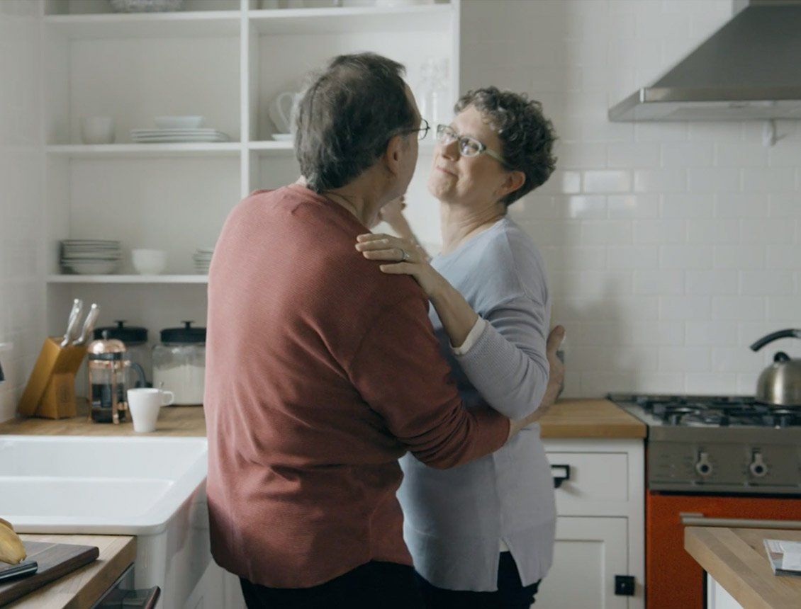 A man and a woman are dancing in a kitchen.