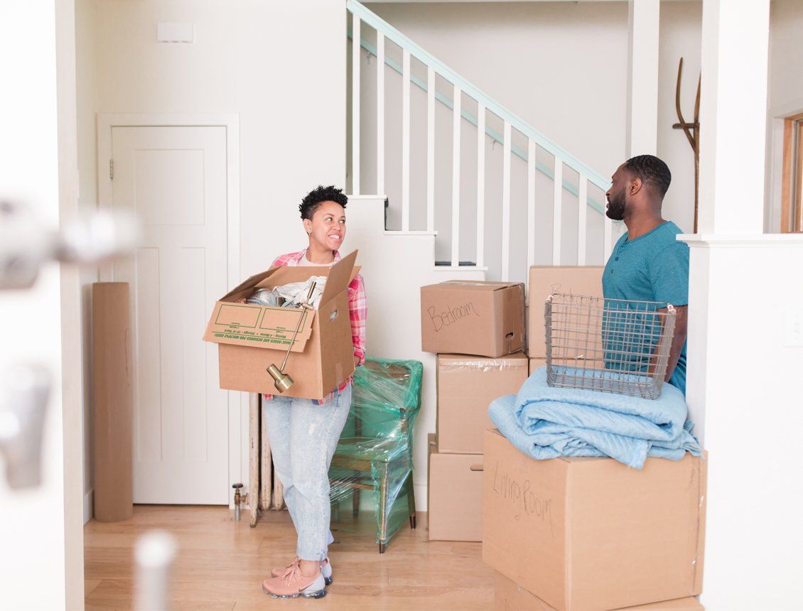 Behind the scenes image of Spin Creative's brand spot shoot for Harborstone Credit Union. The image features a couple carrying boxes into their home that they recently purchased.