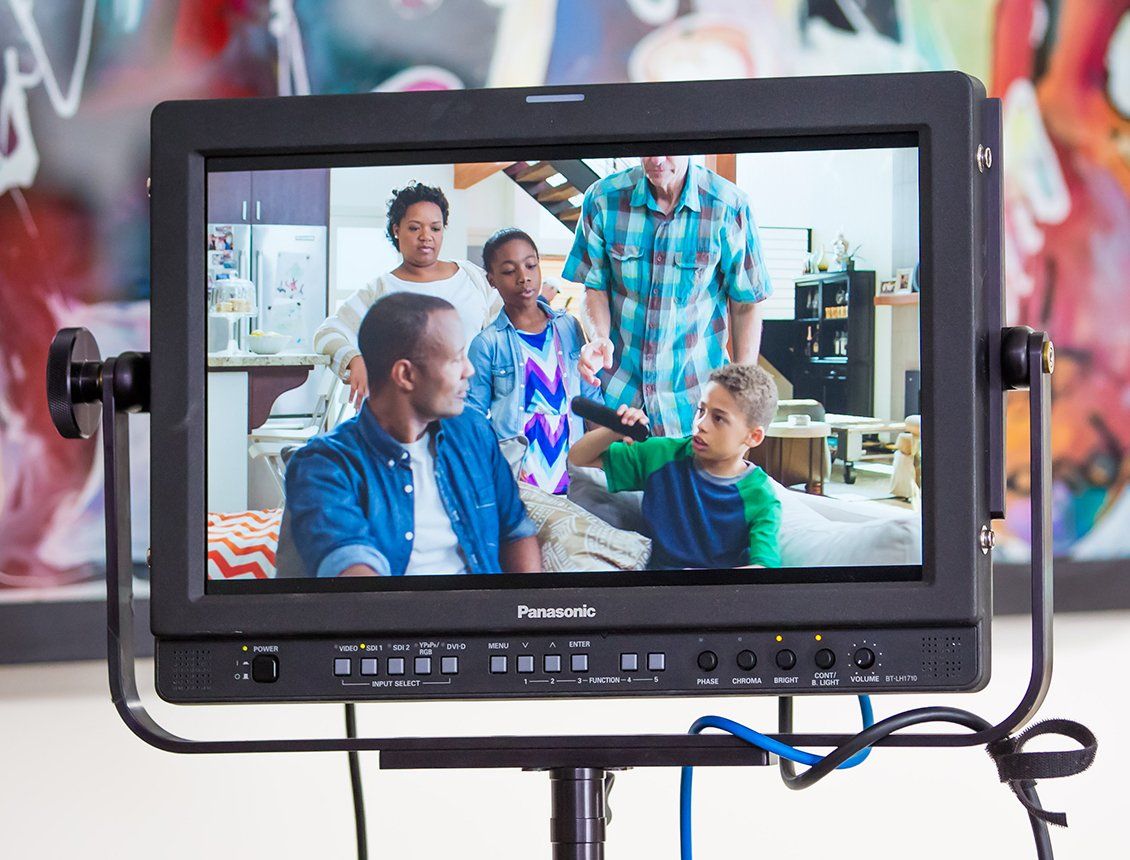 A monitor shows a family sitting on a couch