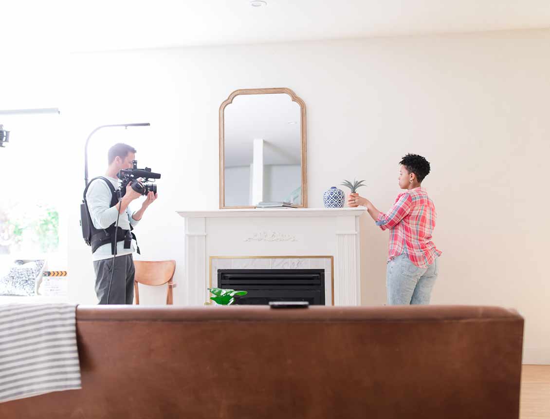 A man is taking a picture of a woman in a living room.