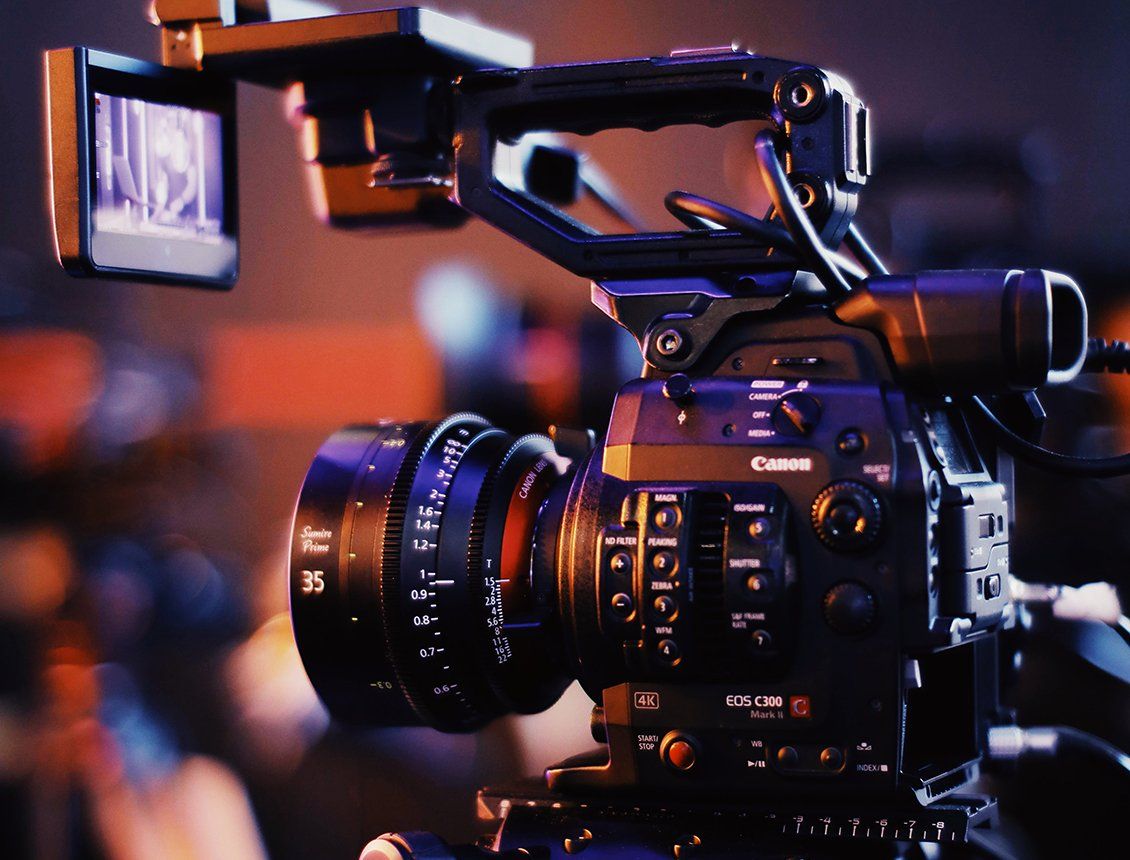 Close up image of Canon cinema camera with a cinema lens A canon camera is sitting on a tripod in a dark room