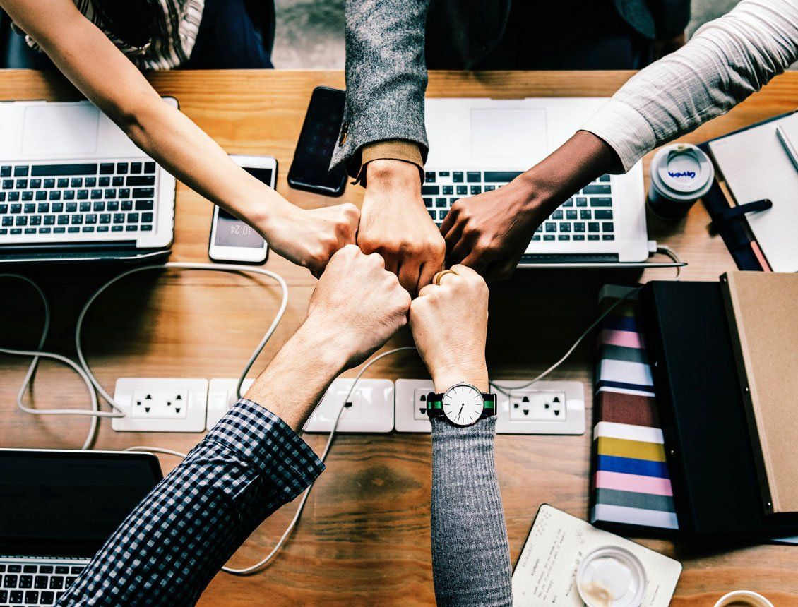 A group of people are putting their hands together on a desk.