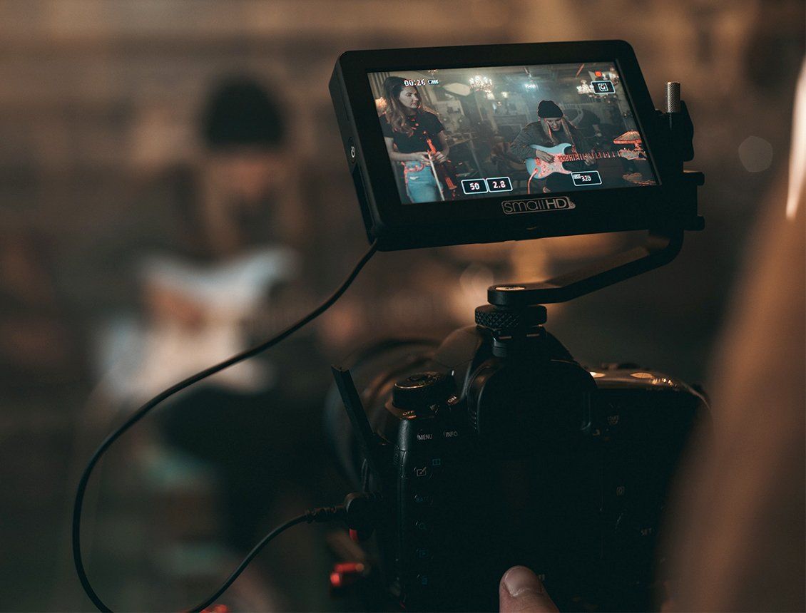 Camera with attached monitor displaying a blurry indoor scene of people.