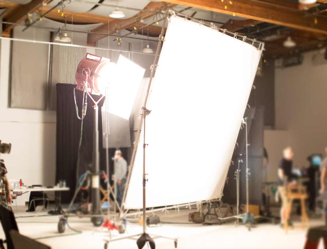 A blurred image of a movie set with a large white screen.