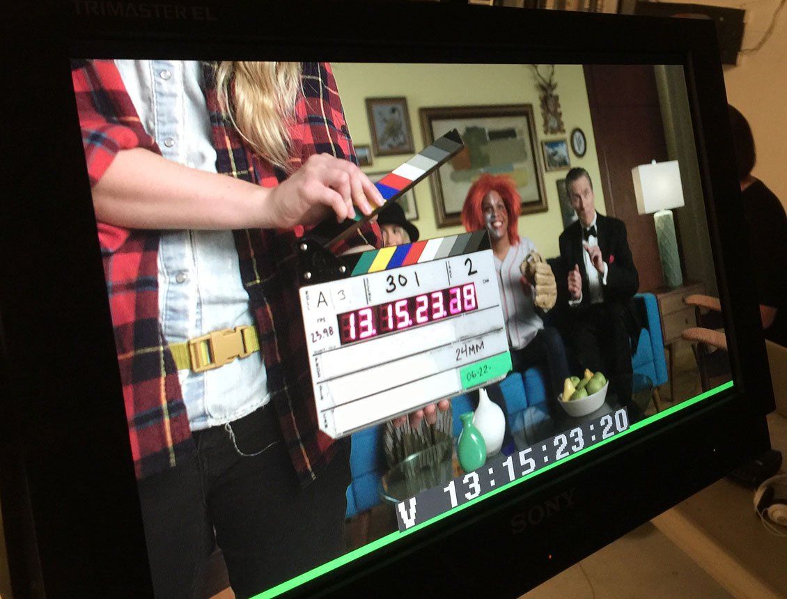 A person is holding a clapper board in front of a television screen.