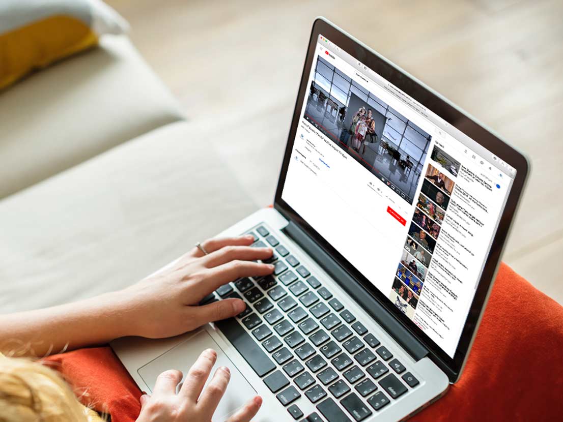 A woman is sitting on a couch using a laptop computer.