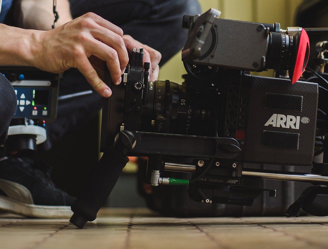 Image of a Arri Alexa cinema camera with a person changing the matte box A person is working on a camera that says arri on it