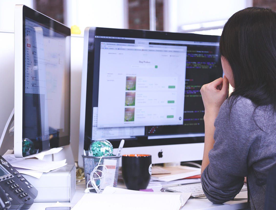 A woman is sitting at a desk looking at a computer screen