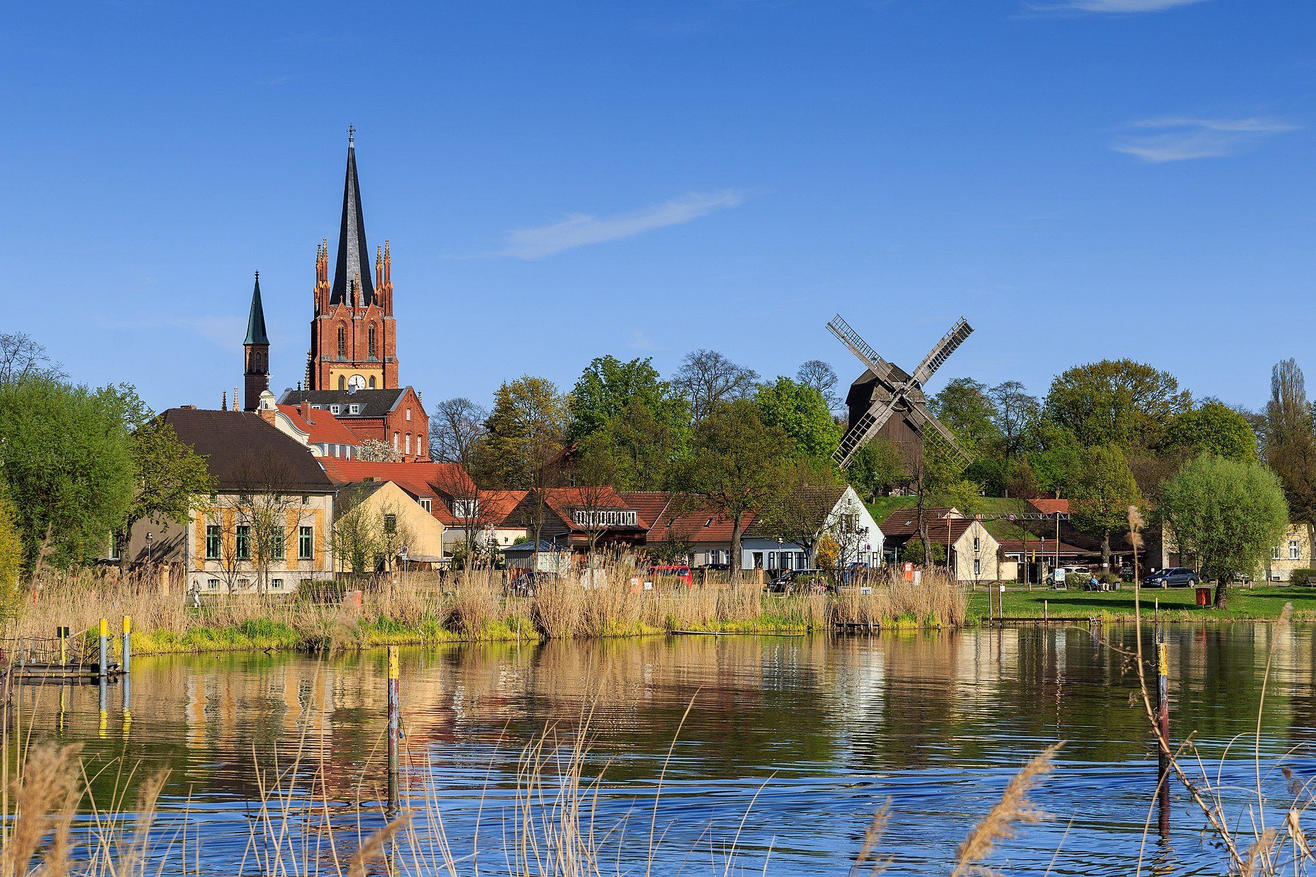 Ein See mit einer Windmühle und einer Kirche im Hintergrund