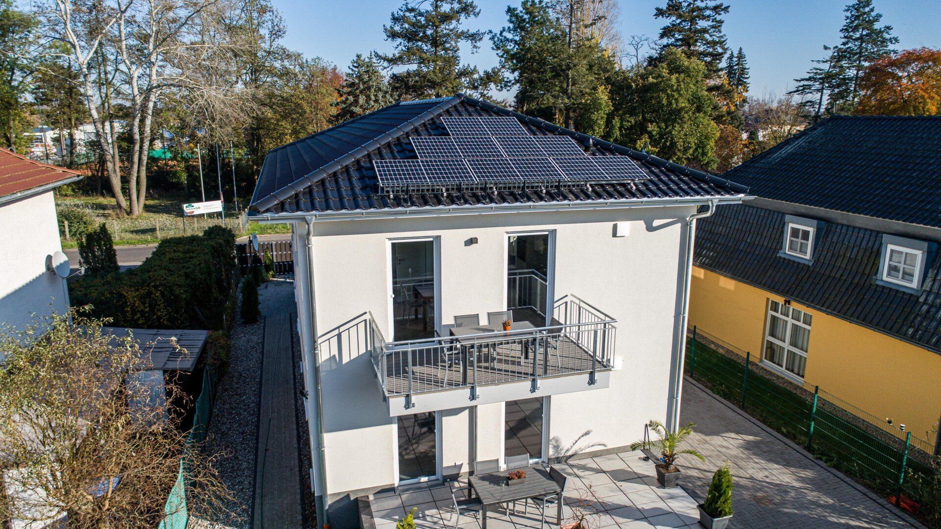Eine Luftaufnahme eines Hauses mit Balkon und Sonnenkollektoren auf dem Dach.