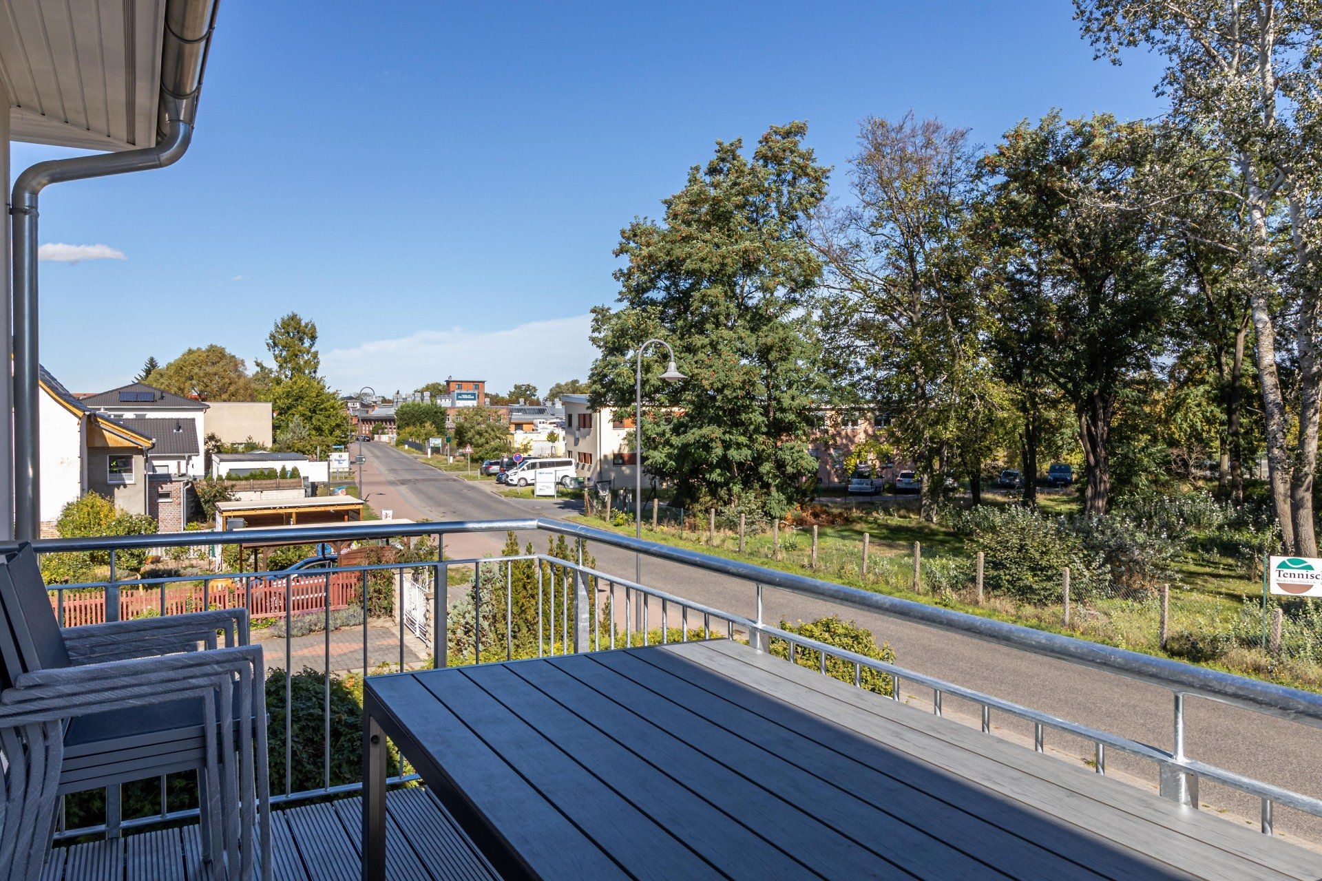 Ein Balkon mit Tisch und Stühlen mit Blick auf eine Straße.