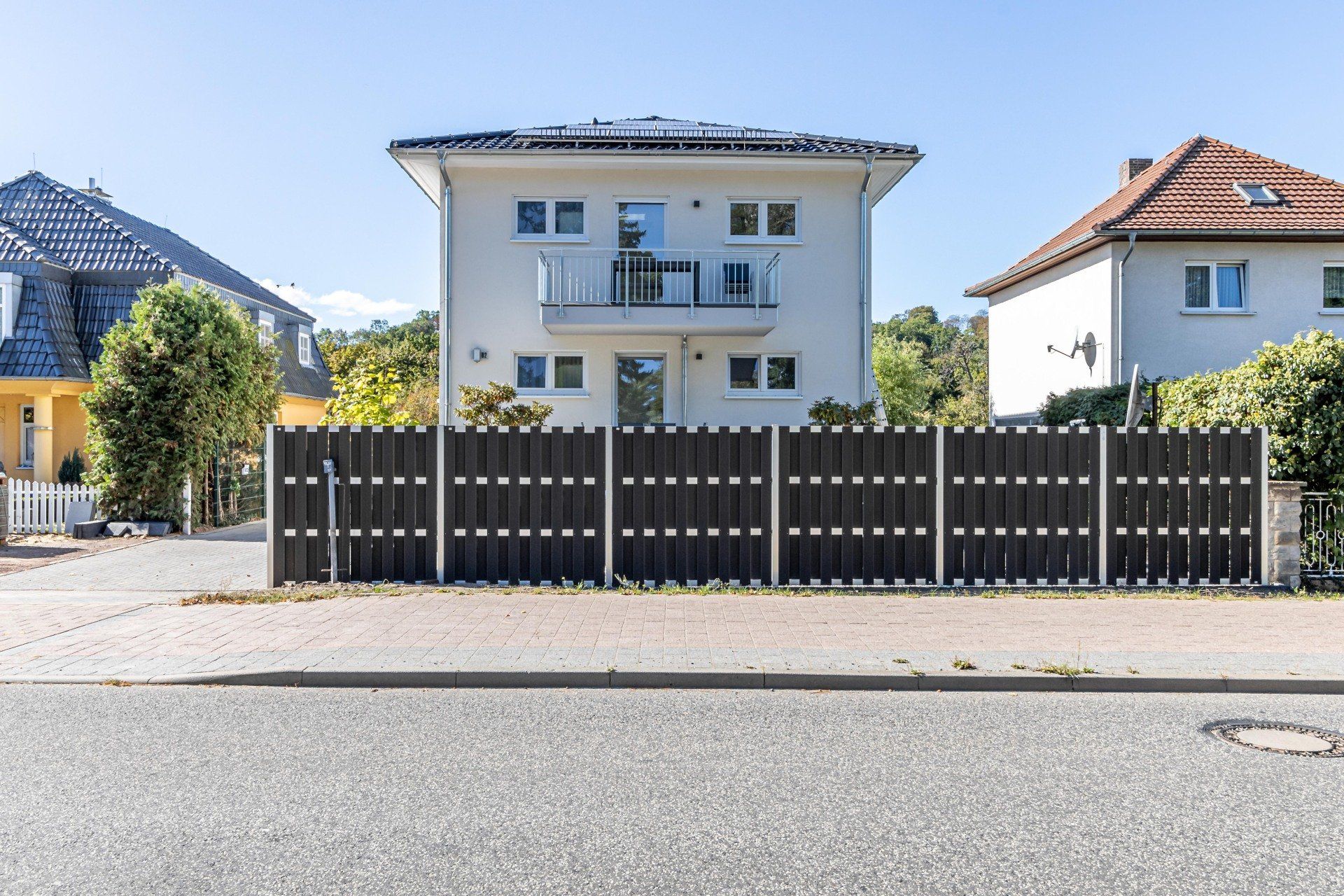 Ein weißes Haus mit einem schwarzen Zaun davor