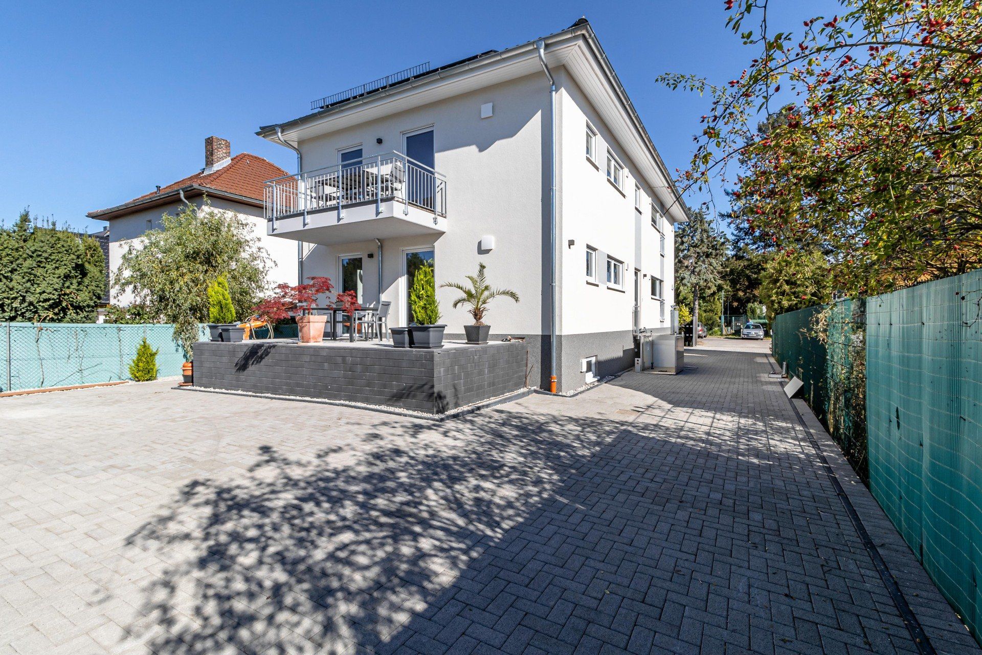 Ein großes weißes Haus mit einem Balkon und einem grünen Zaun