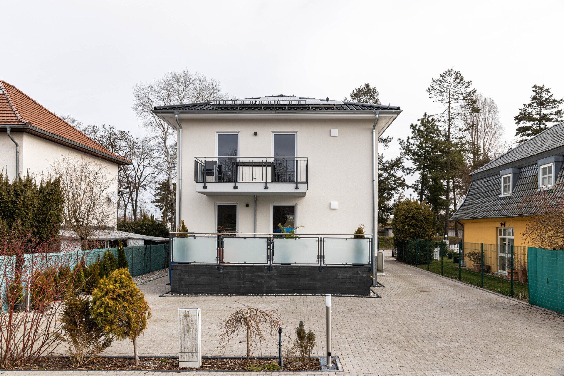 Ein weißes Haus mit Balkon und einer Auffahrt davor.