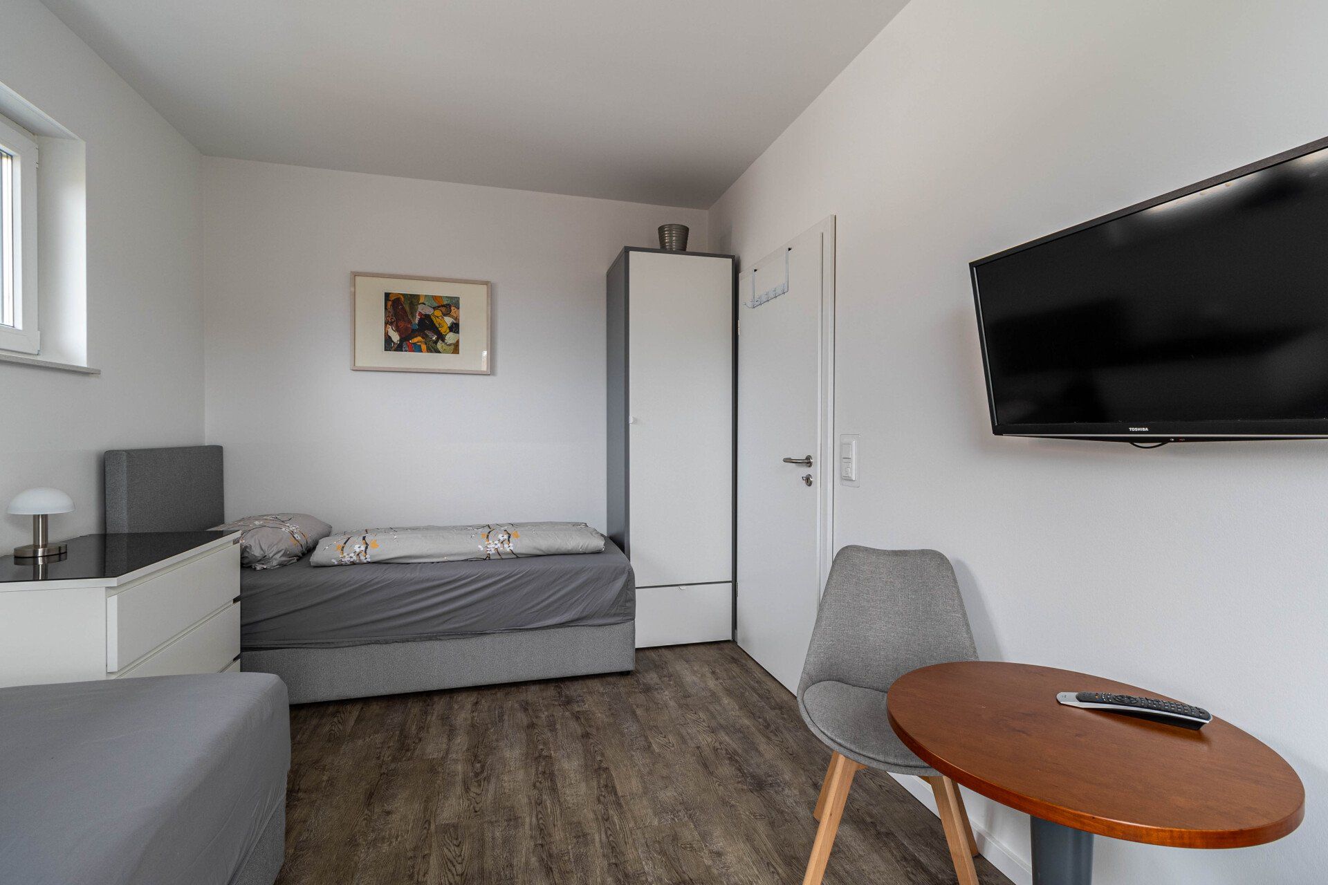 Ein Schlafzimmer mit Bett, Stuhl, Tisch und Fernseher.