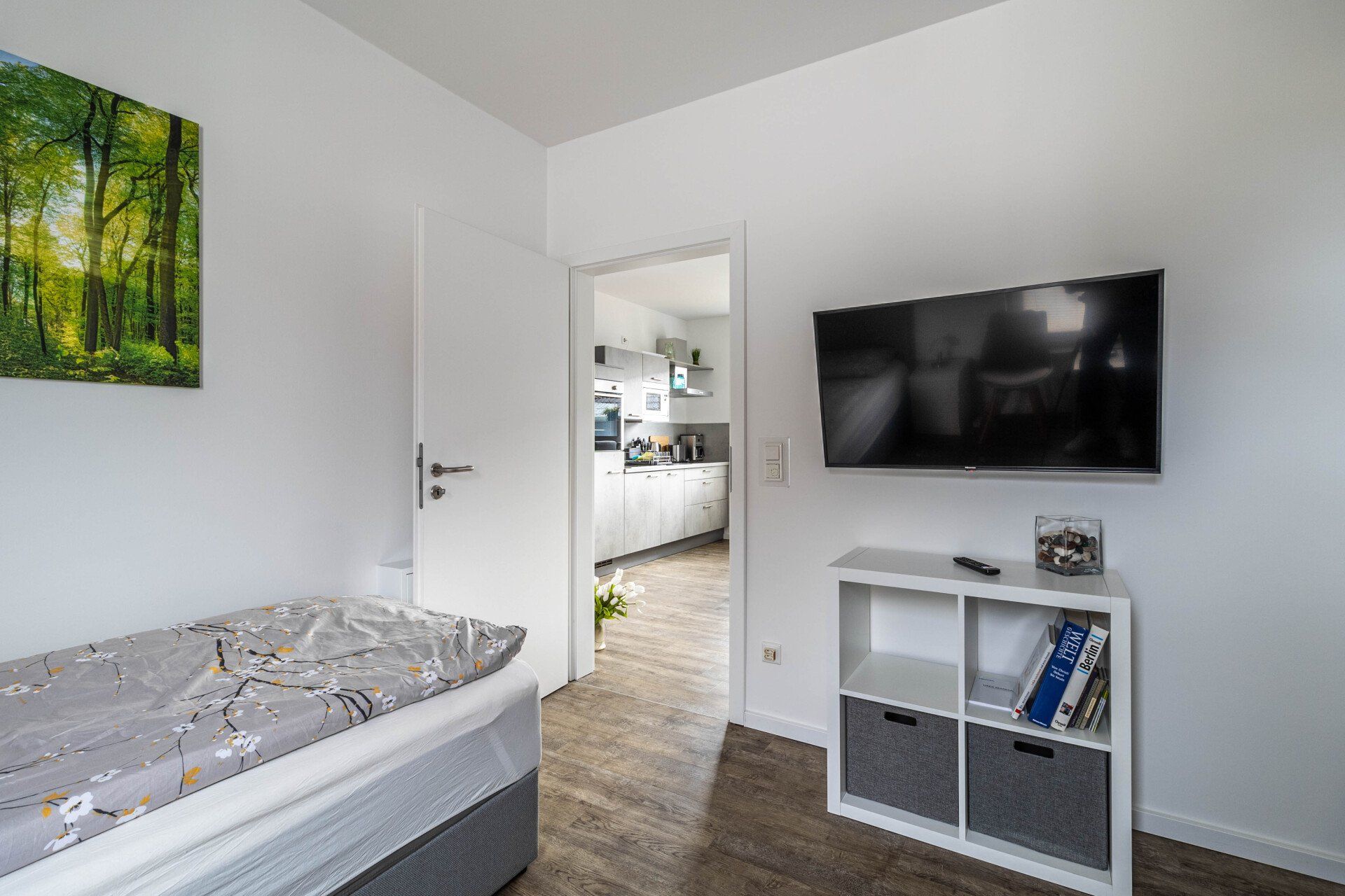 Ein Schlafzimmer mit einem Einzelbett und einem Flachbildfernseher an der Wand.