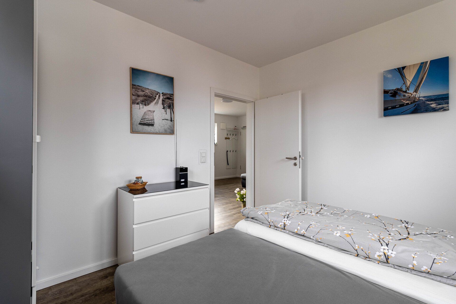 Ein Schlafzimmer mit Bett, Kommode und Gemälden an der Wand.