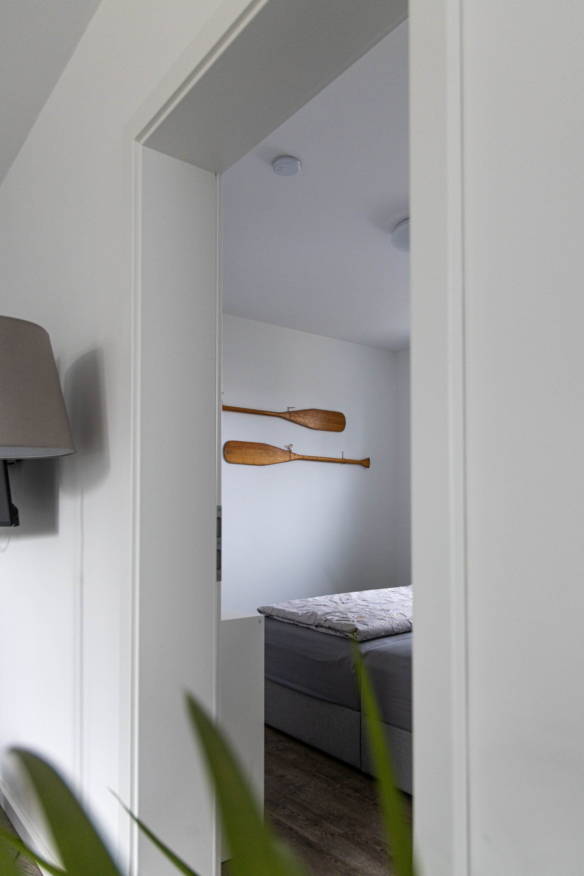 Eine Tür, die zu einem Schlafzimmer mit zwei Rudern an der Wand führt.
