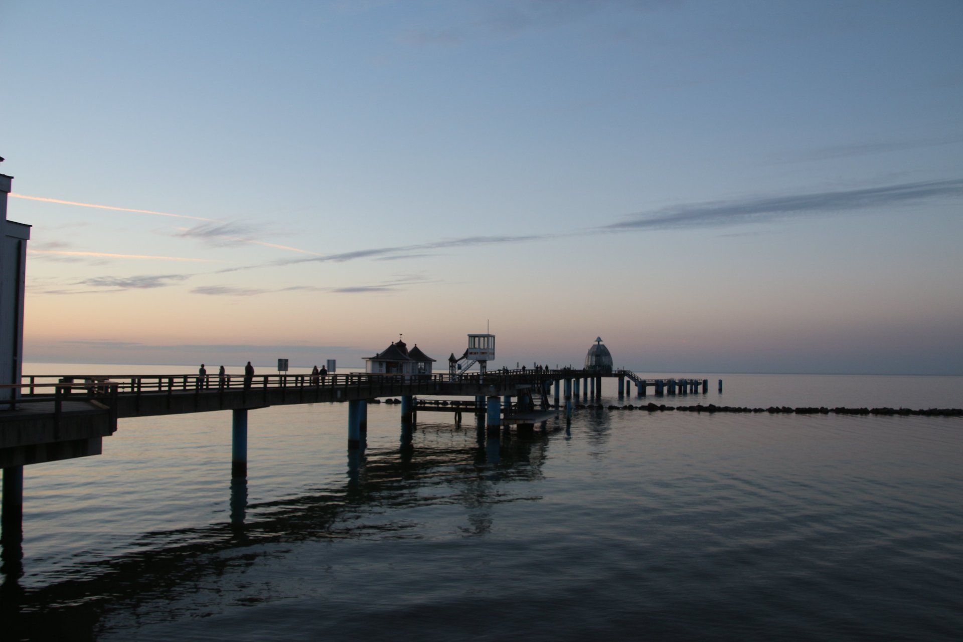 Ein Pier mit Blick auf ein Gewässer bei Sonnenuntergang.