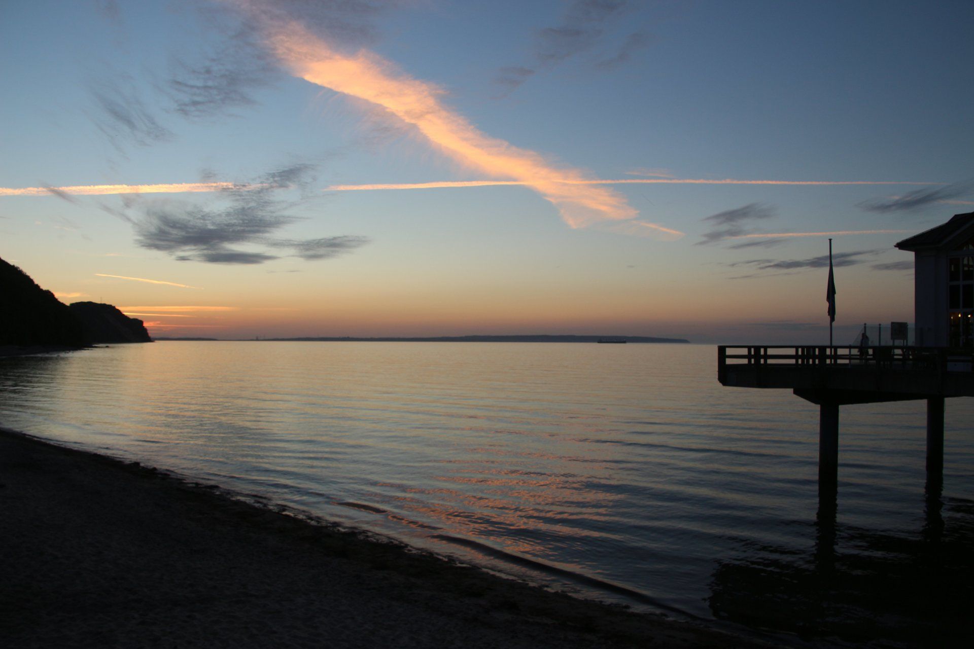Ein Sonnenuntergang über einem Gewässer mit einem Dock im Vordergrund