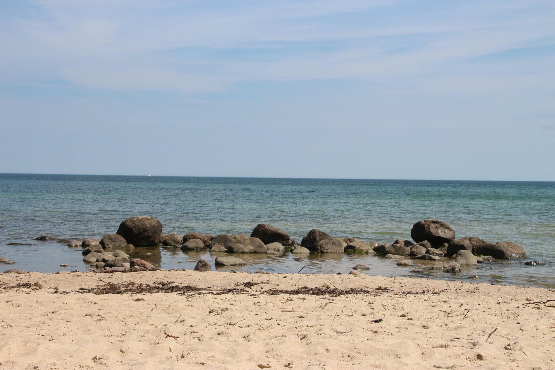 Ein Strand mit Felsen im Wasser und einem blauen Himmel