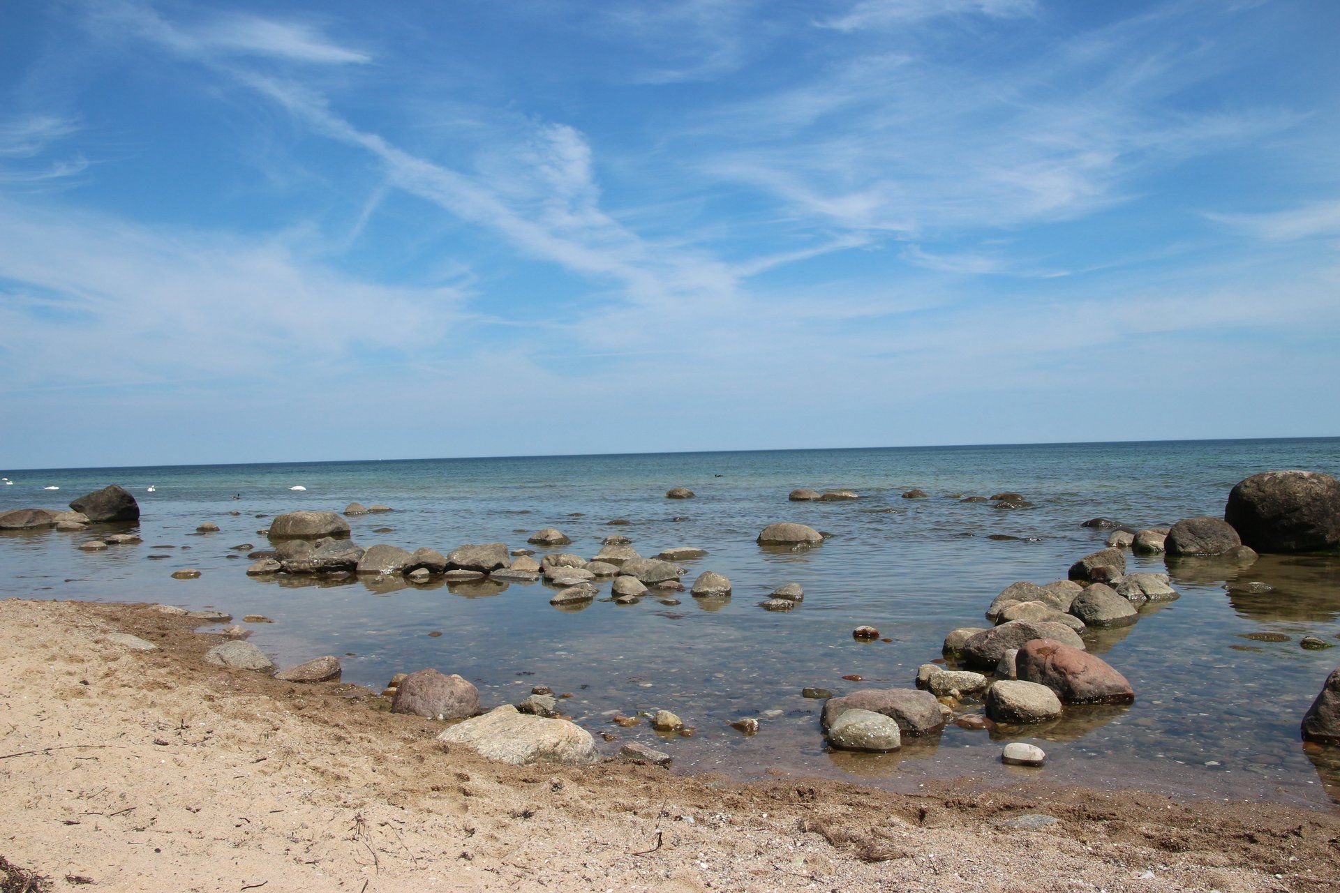 Ein Strand mit Felsen im Wasser und einem blauen Himmel