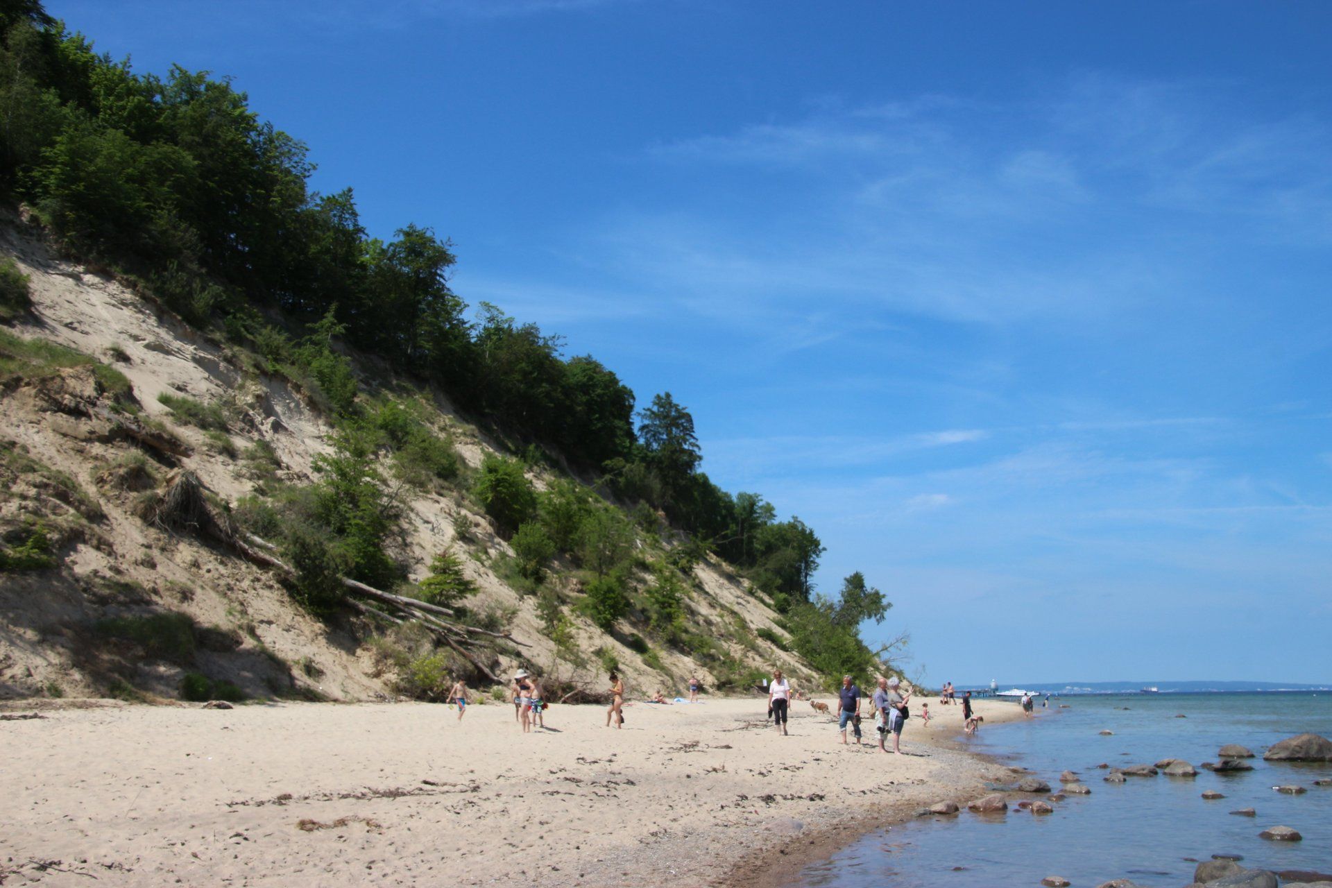 Eine Gruppe von Leuten geht an einem Strand in der Nähe einer Klippe spazieren.