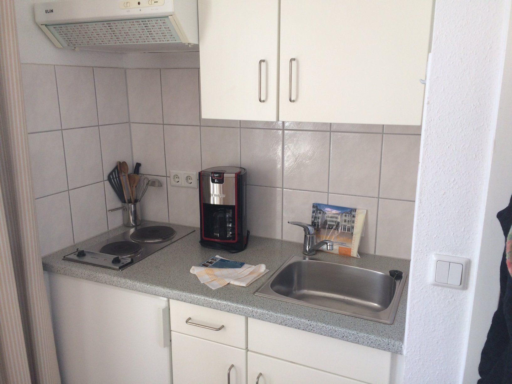 Eine kleine Küche mit weißen Schränken und einer Spüle