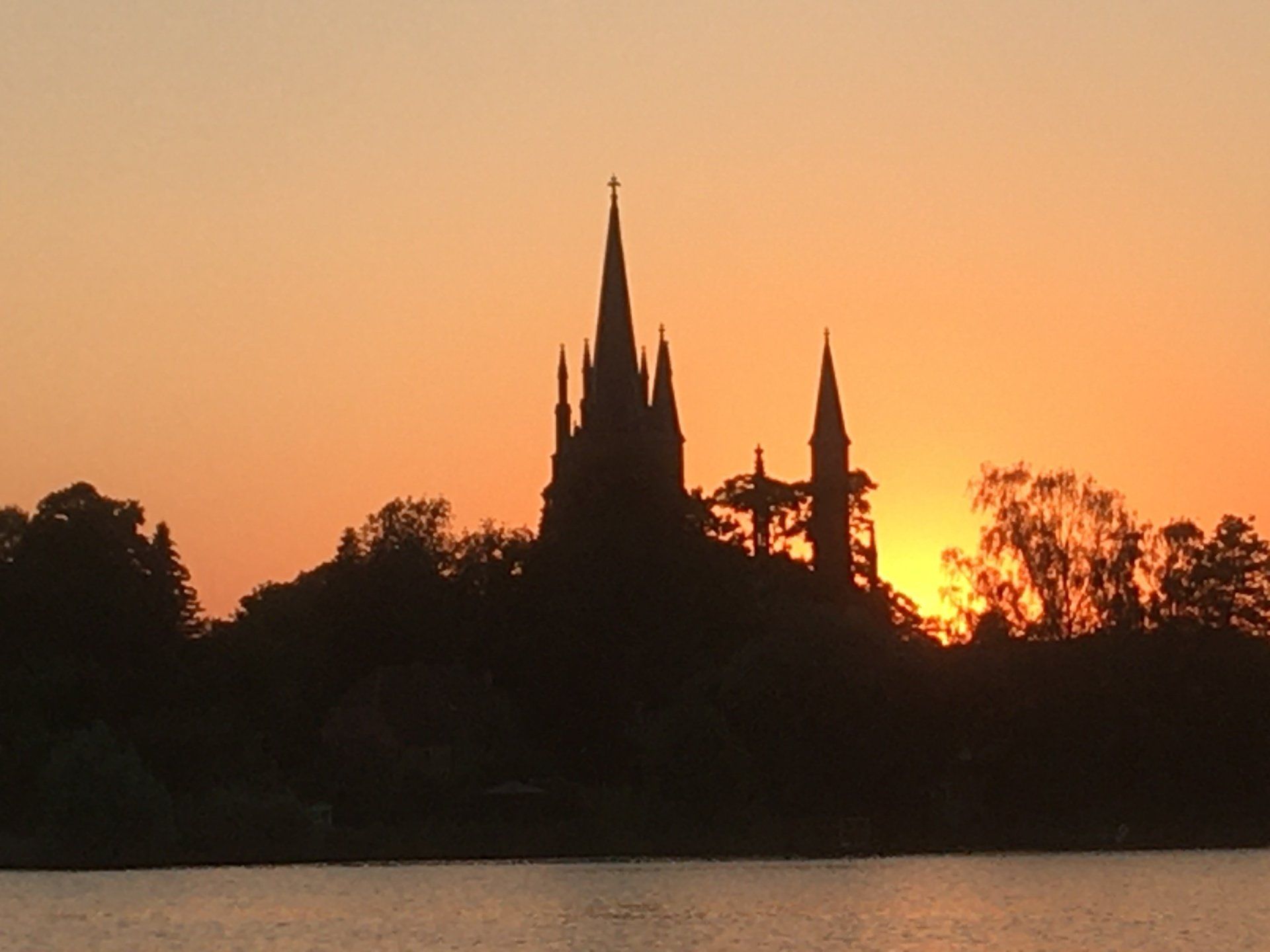 Die Silhouette einer Burg steht im Sonnenuntergang über einem See