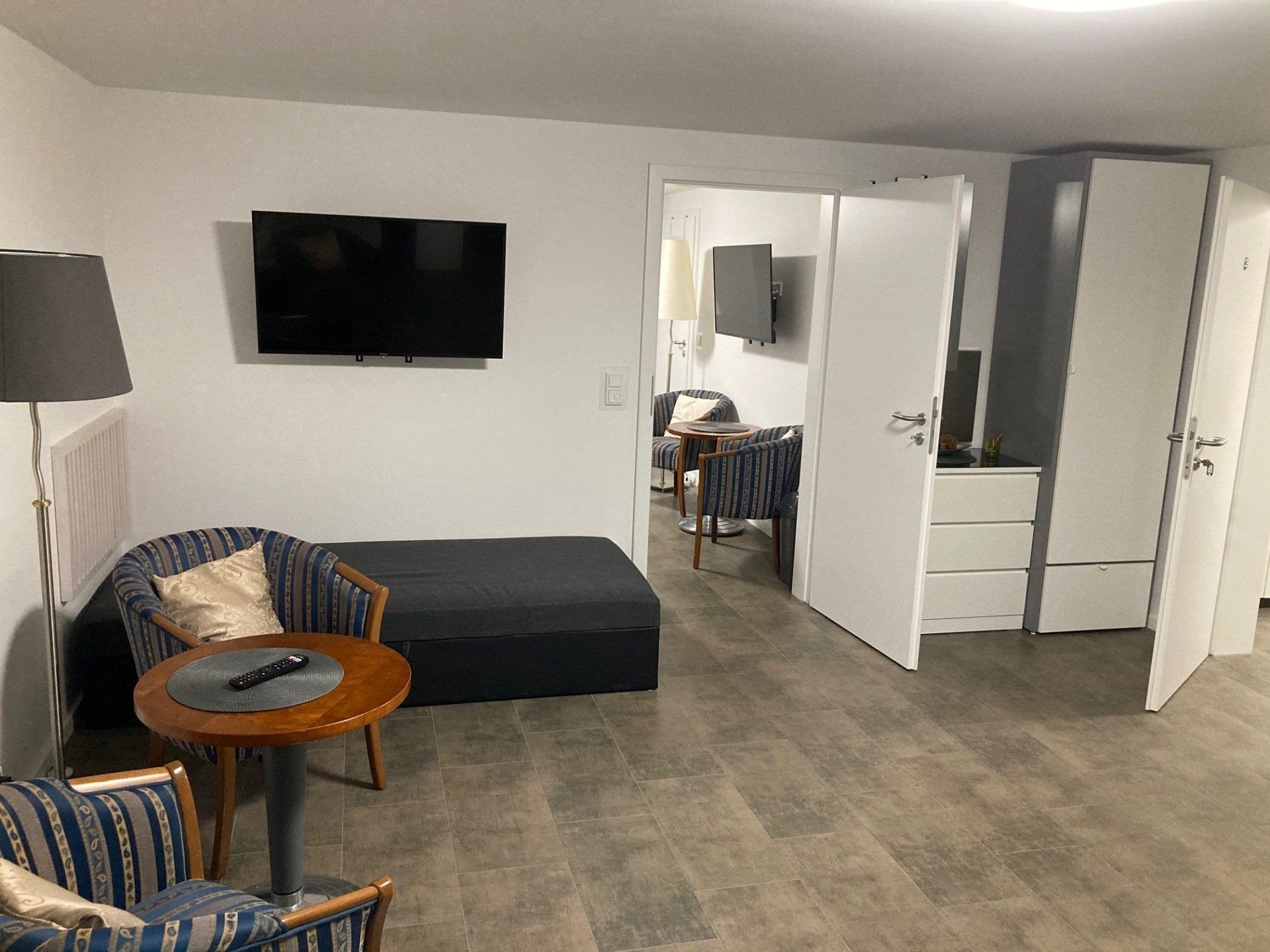Ein Wohnzimmer mit Couch, Sessel, Tisch und Fernseher.