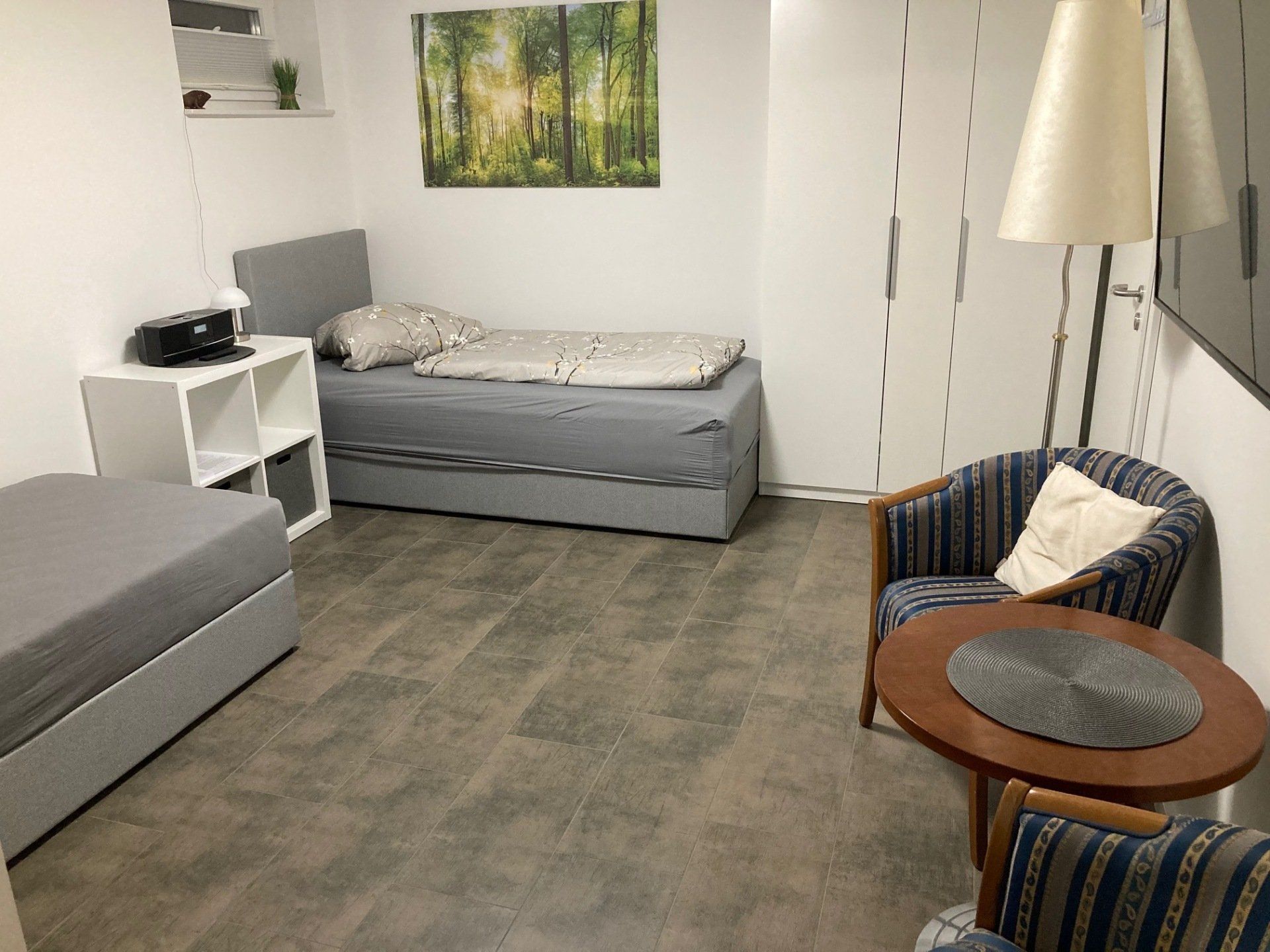 Ein Schlafzimmer mit zwei Betten, einem Stuhl, einem Tisch und einer Lampe.