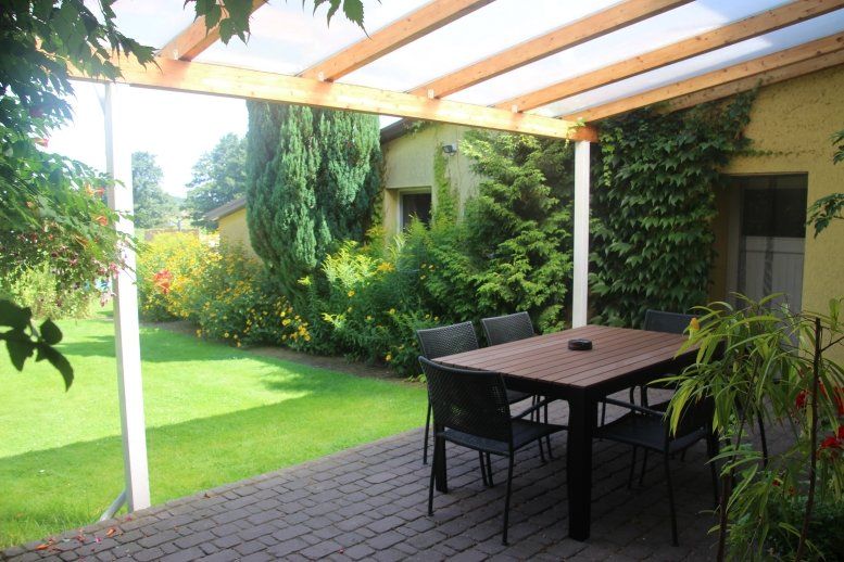 Eine Terrasse mit Tisch und Stühlen unter einer Pergola