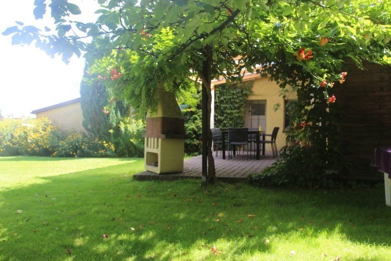 Ein Hinterhof mit einem Grill und einem Tisch und Stühlen unter einem Baum