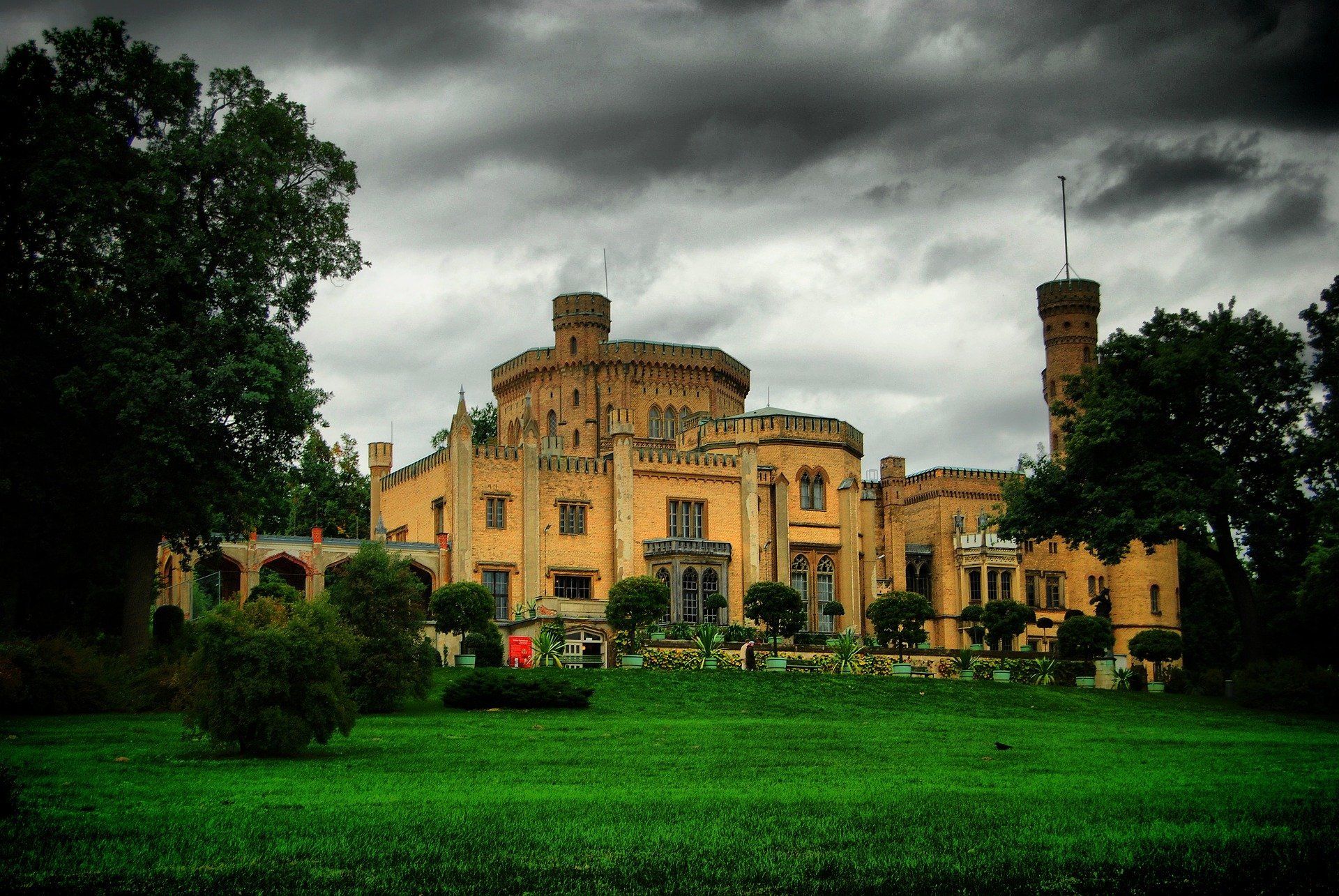 Ein großes Schloss ist an einem bewölkten Tag von Bäumen und Gras umgeben