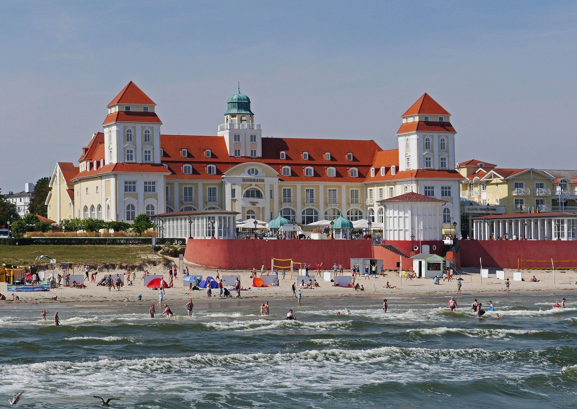 Ein großes Gebäude mit einem roten Dach liegt neben einem Strand